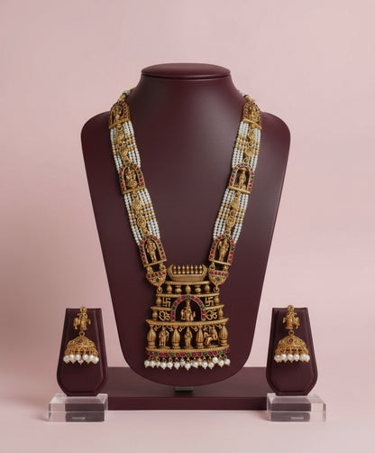Gold necklace with matching earrings on a mannequin bust against a pink background