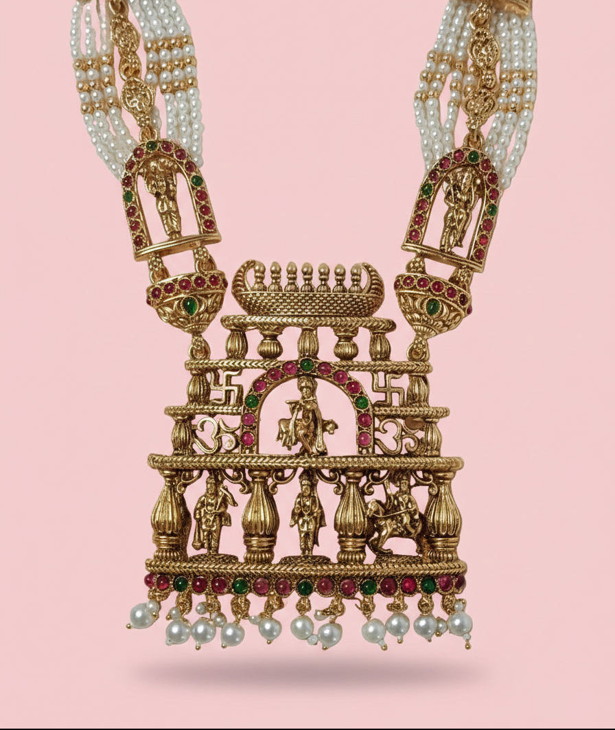 Ornate gold necklace with pearls and gemstones on a pink background