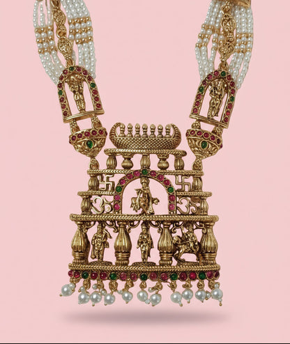 Ornate gold necklace with pearls and gemstones on a pink background