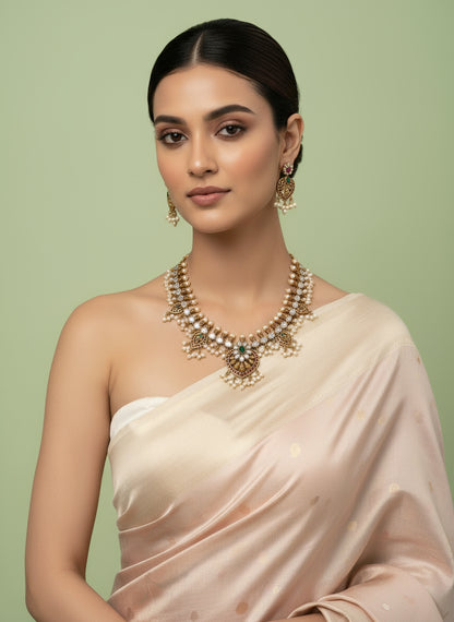 Woman wearing a beige saree with gold jewelry on a light green background