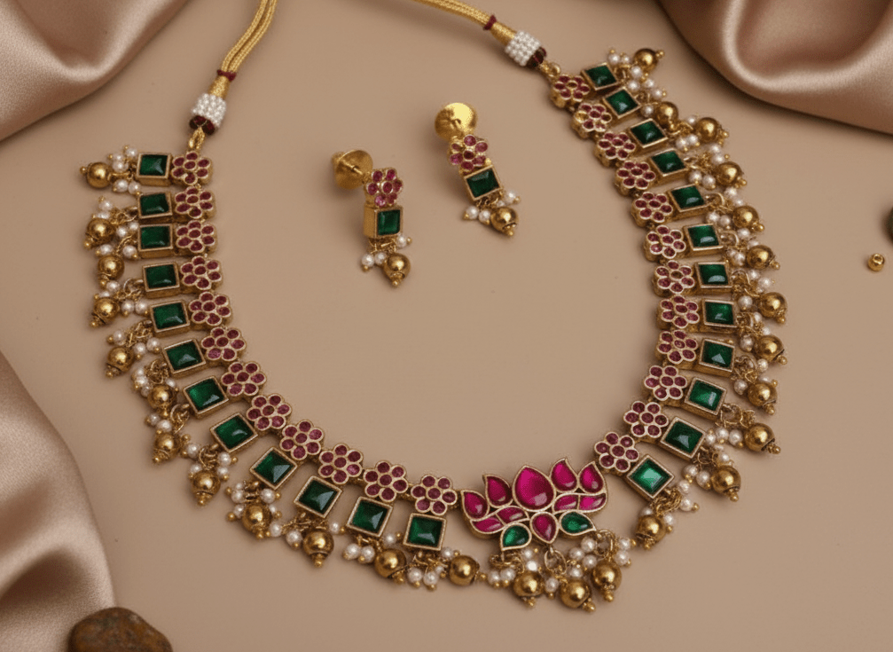 This necklace features square green stones alternating with pink floral clusters, all set in a rich gold framework.