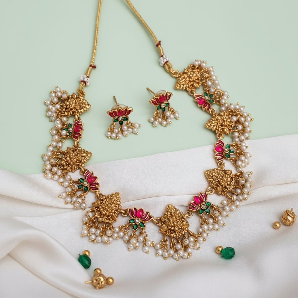 Necklace set featuring gold Lakshmi motifs with pink and green enamel lotus accents, finished with clusters of pearls.