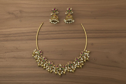 This gold-toned necklace and earring set features pink and green lotus motifs enhanced by delicate pearl hangings.