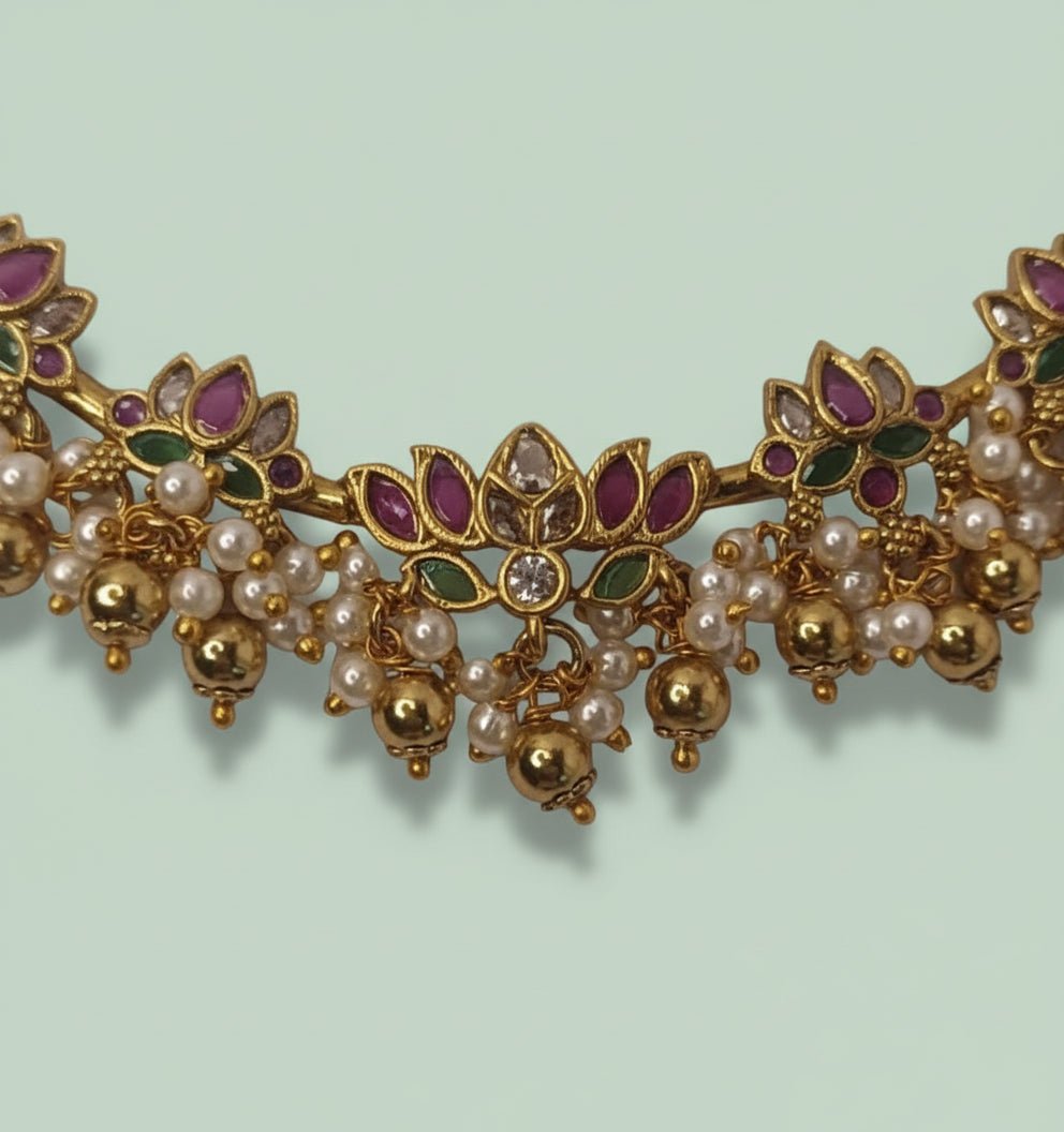 This gold-toned necklace and earring set features pink and green lotus motifs enhanced by delicate pearl hangings.